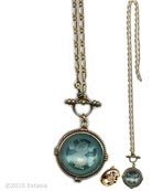 From our Marlene Collection, Aqua transparent German glass intaglio set in a domed back pendant on long chain. The delicate metalwork on the back of the pendant is a wonderful finishing touch. Medium size pendant is 1 inch in diameter. Long chain measures 21 inches. Shown in our signature bronze metal. Each necklace made to order in the U.S.A.